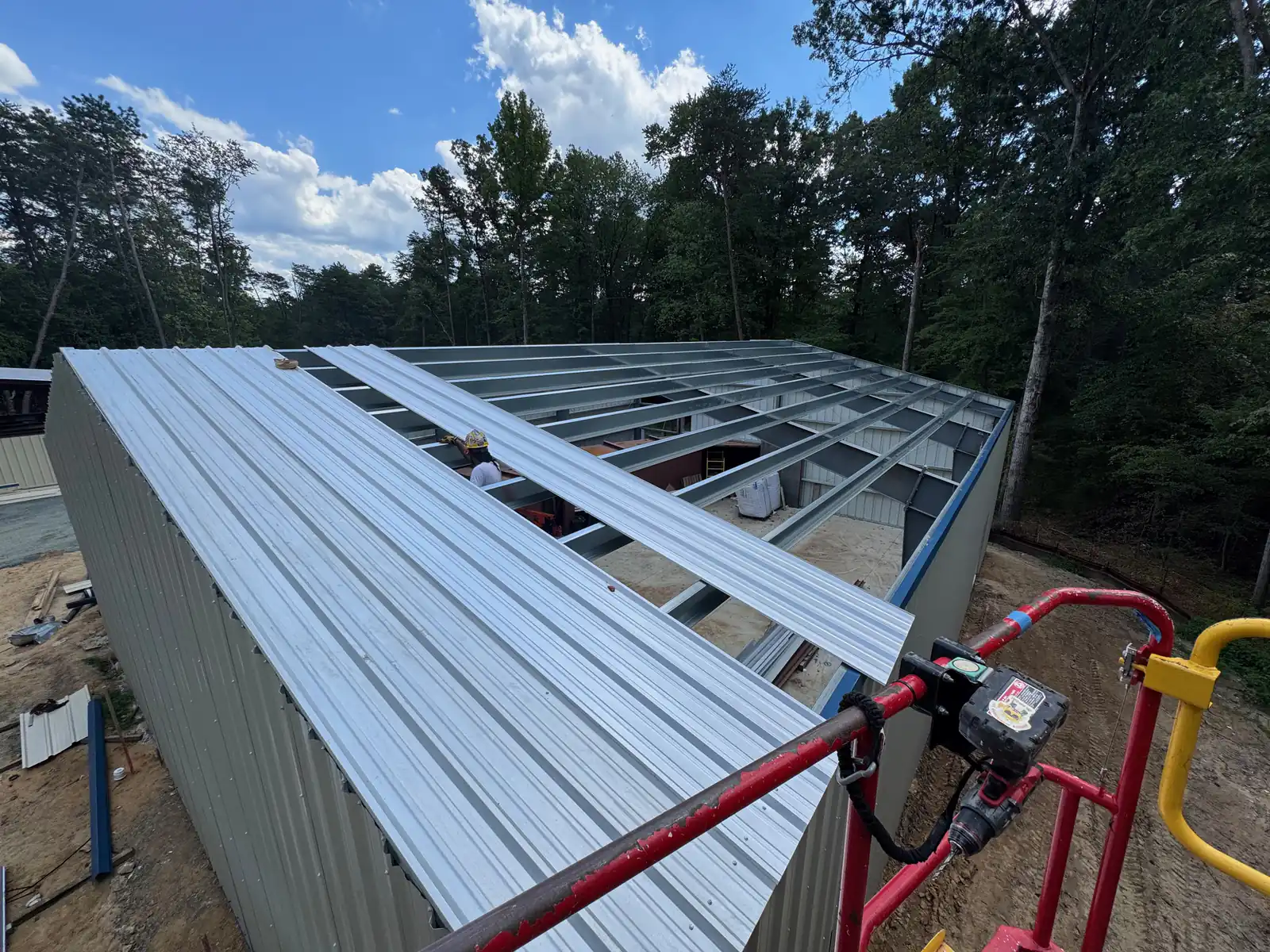 Metal roof panels being run over open steel purlins on a clear-span steel building