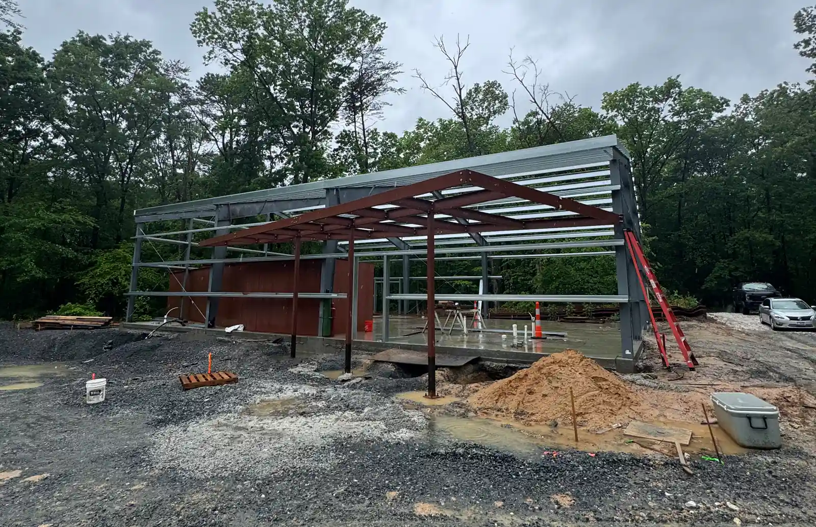 Steel building frame erection in progress with rigid frames, eave struts and roof purlins set on the slab